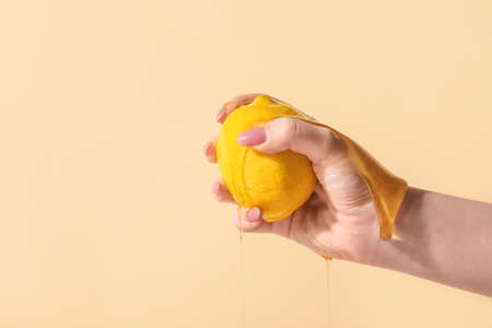 Female hand with honey and lemon on color background, closeupの写真素材