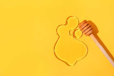 Wooden dipper and honey on color background, closeupの写真素材