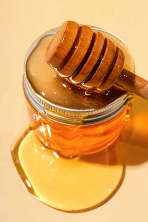 Jar of cosmetic product, dipper and honey on color background, closeupの写真素材