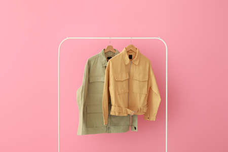 Rack with green and yellow jackets near pink wall