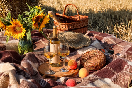 Festive picnic with sunflowers and wine on wheat fieldの写真素材