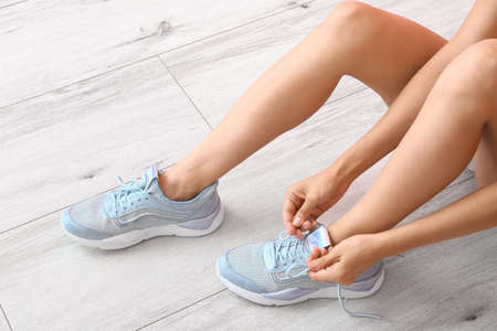 Young woman tying shoe laces indoors