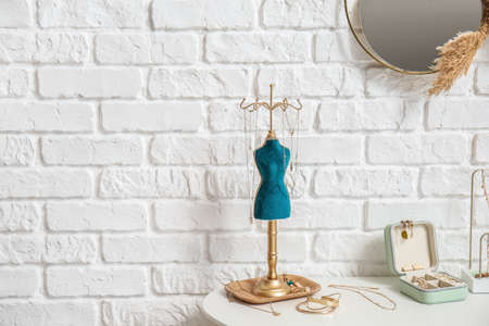Stand and box with jewelry on table near white brick wallの写真素材