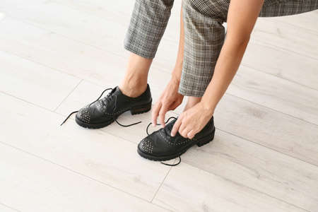 Young woman tying shoe laces at homeの写真素材