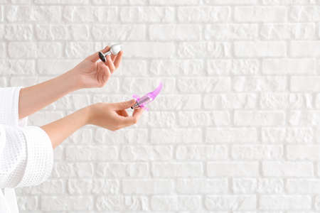 Young woman with sex toys on white brick background