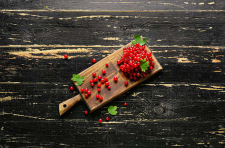 Board with fresh red currants and leaves on dark wooden backgroundの写真素材