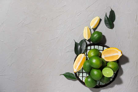 Plate with tasty limes on gray background