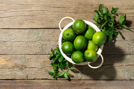 Colander with tasty limes on wooden backgroundの写真素材