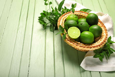 Basket with tasty limes on wooden backgroundの写真素材