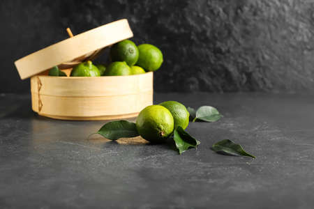 Basket with tasty limes on dark background
