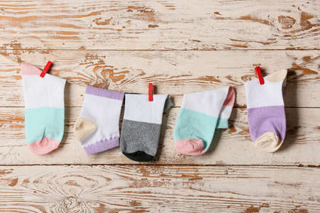 Many different socks hanging on rope against light wooden background