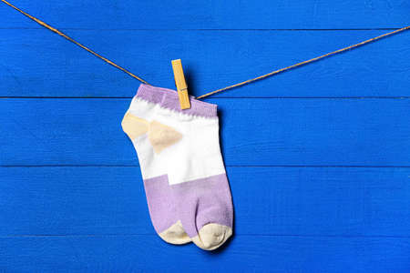 Pair of socks hanging on clothesline against color wooden backgroundの写真素材