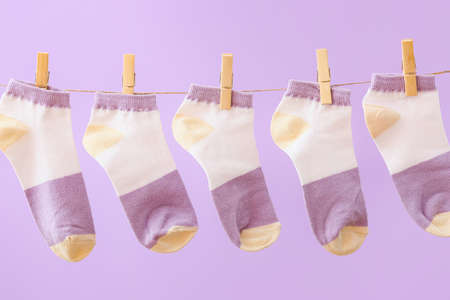 Many socks hanging on rope against lilac background, closeupの写真素材