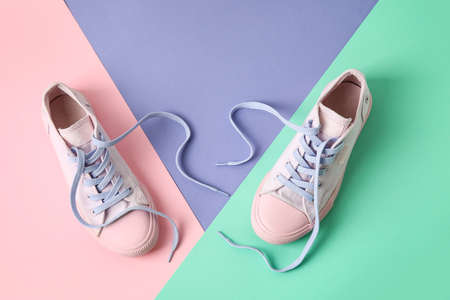 Pair of shoes with untied laces on color backgroundの写真素材