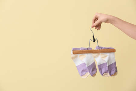 Woman holding hanger with socks on color backgroundの写真素材