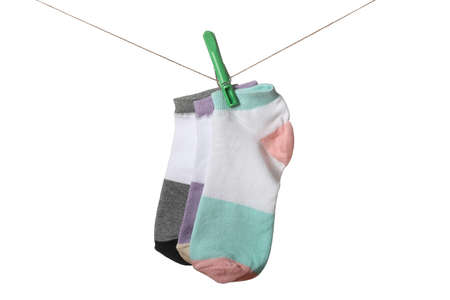 Different socks hanging on clothesline against white background