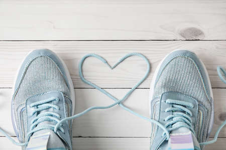 Pair of sportive shoes with heart made of laces on light wooden background, closeupの写真素材