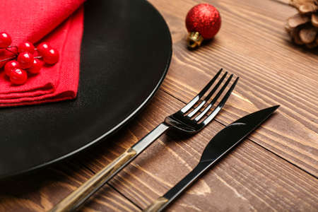 Plate and set of cutlery for Christmas celebration on wooden background