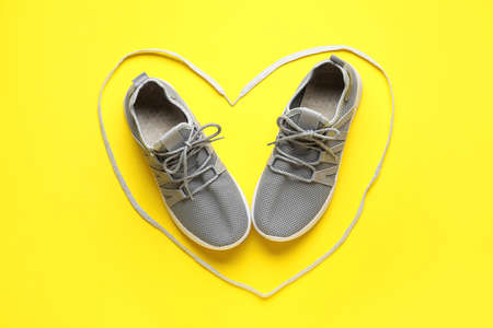 Pair of sportive shoes in heart made of lace on color backgroundの写真素材