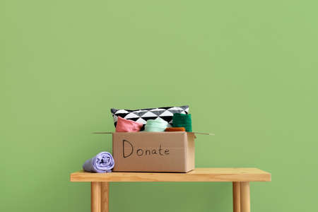 Cardboard box with donations on bench against green backgroundの写真素材