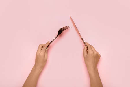 Woman with fork and knife on color background