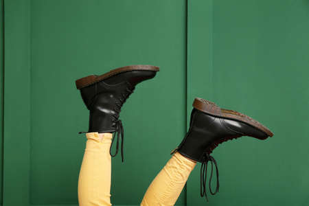 Legs of woman in black boots on green background