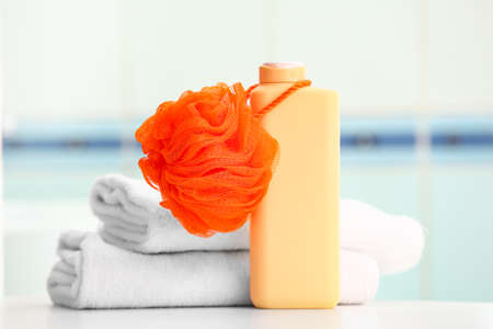 Bottle of cosmetic product, bath sponge and clean towels on tableの写真素材