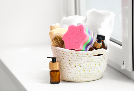 Basket with different bath accessories and cosmetics on windowsillの写真素材