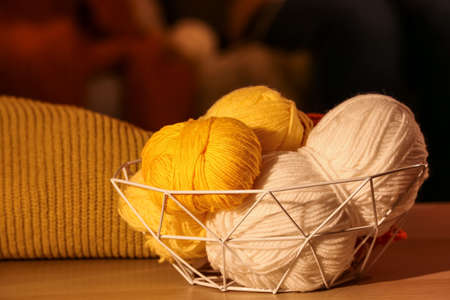 Basket with knitting yarn on table in room
