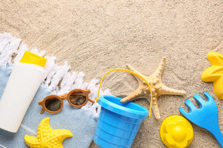 Set of beach accessories for children and bottle of sunscreen on sandの写真素材