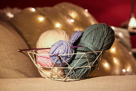 Basket with knitting yarn and needles on sofa, closeupの写真素材