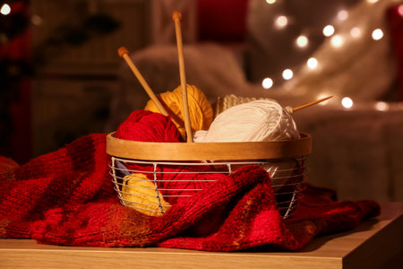 Basket with knitting yarn and needles on wooden table in roomの写真素材