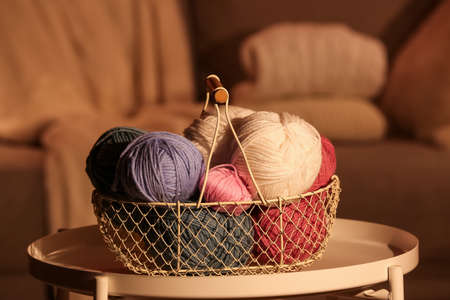 Basket with knitting yarn on table in roomの写真素材