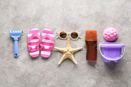 Set of beach accessories for children, bottle of sunscreen and starfish on grunge background