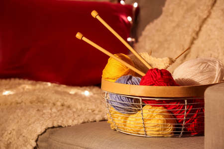 Basket with knitting yarn and needles on sofa in roomの写真素材