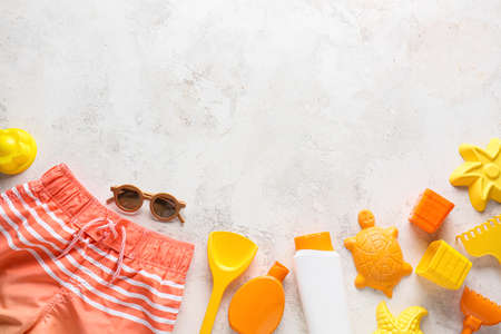 Set of beach accessories for children, swimsuit and bottles of sunscreen on light backgroundの写真素材