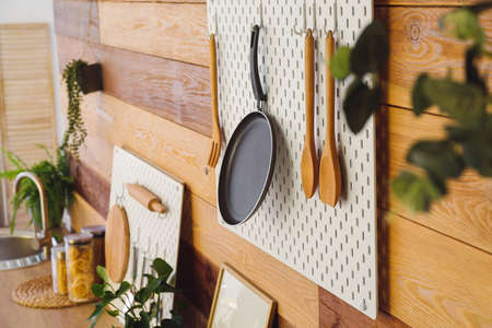 Peg board with frying pan and spatulas hanging on wooden wallの写真素材
