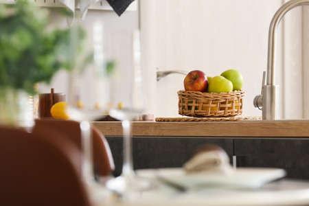 Wicker basket with apples on table in kitchenの写真素材
