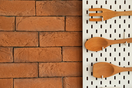 Peg board with wooden spatulas hanging on brick wall, closeupの写真素材