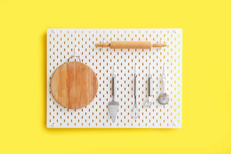 Peg board with kitchenware hanging on yellow wallの写真素材