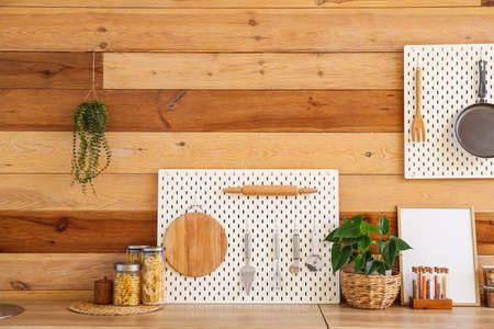 Peg board with kitchenware on kitchen counter near wooden wallの写真素材