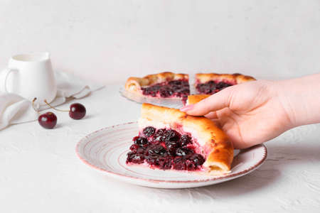 Woman eating tasty cherry khachapuri on light background