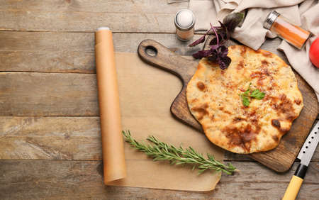 Board with tasty khachapuri and spices on wooden background