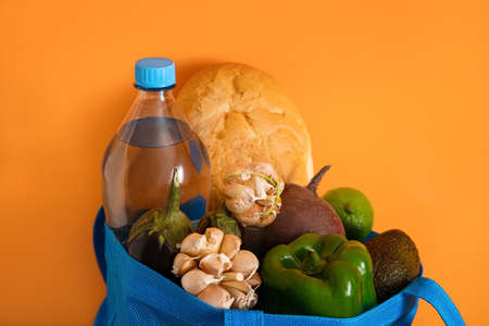Eco bag with different products on color background