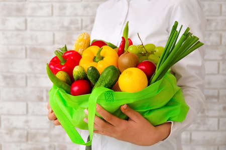 Woman holding bag with food on brick background