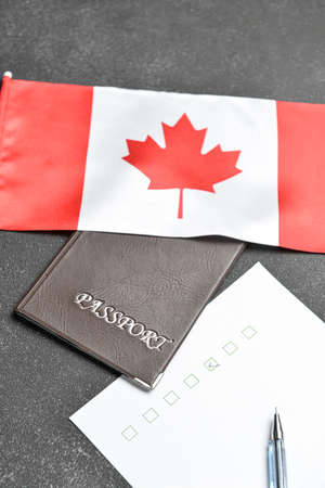 Canadian flag with passport, pen and voting sheet on dark background