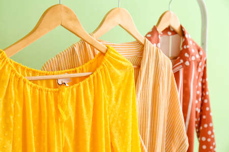 Hanger with trendy dresses near color wall, closeupの写真素材