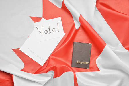 Paper sheets with word VOTE and passport on Canadian flagの写真素材
