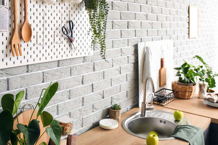 Pegboard with kitchenware on gray brick wall in modern kitchen