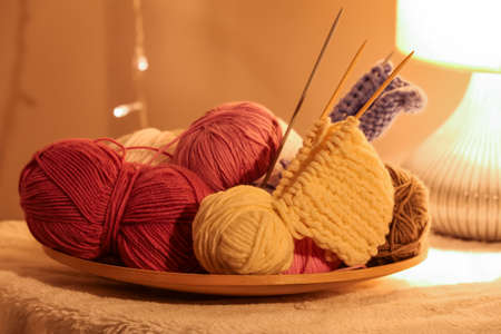 Plate with knitting yarn and needles on table, closeup